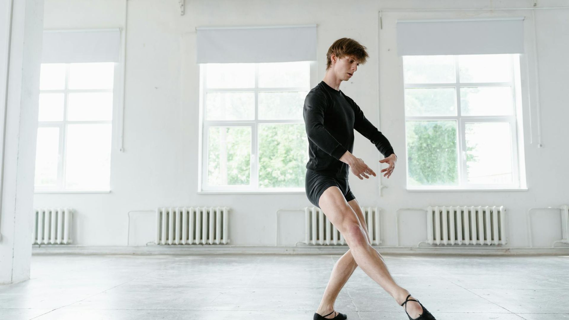 Man performing a controlled bodyweight exercise in a minimalist environment.